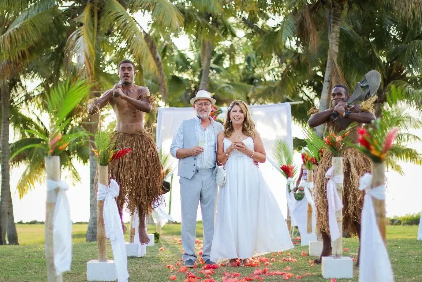 Wedding couple and attendants beneath palms